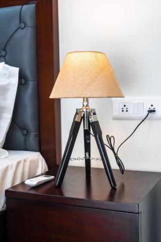 a lamp on top of a table with a bed at The Lodgers 1 BHK Serviced Apartment Golf Course Road Gurgaon in Gurgaon