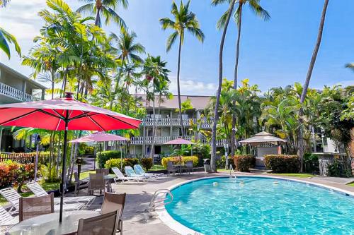 a pool at a resort with chairs and an umbrella at Kona Islander Inn 147 Tropical Oasis in Kailua-Kona