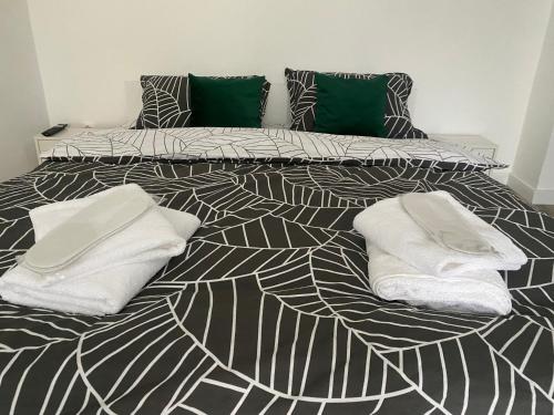 a black and white bed with white towels on it at L&M Apartment in Târgu-Mureş