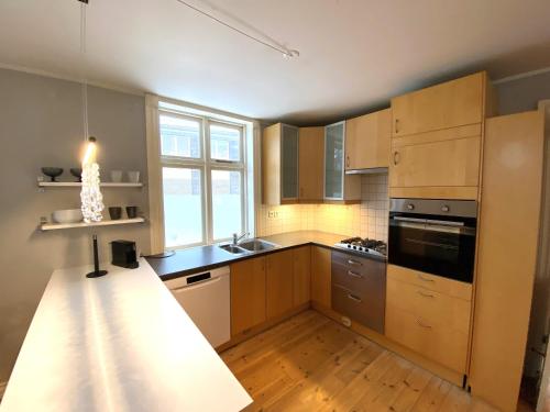 a kitchen with wooden cabinets and a large window at Day Dream Vesturgata 17 Reykjavik in Reykjavík