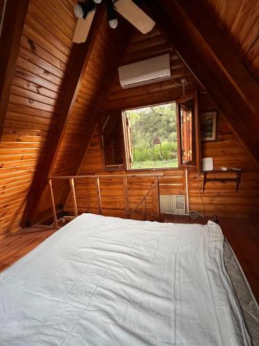 a bed in a wooden room with a window at Cabaña in La Rioja