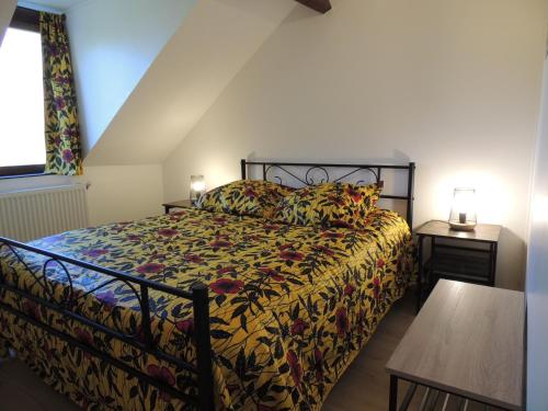 a bedroom with a bed with a floral comforter at LA VILLA QUI A DU CHIEN in Neuville-sur-Touques