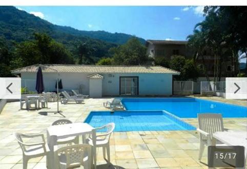 a swimming pool with chairs and a table and a table and chairs at Ubatuba Apartamento temporada in Ubatuba
