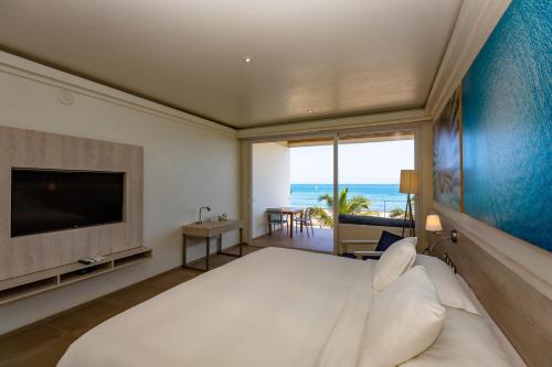 a bedroom with a large bed and a television at Punta Sal Suites & Bungalows Resort in Canoas De Punta Sal