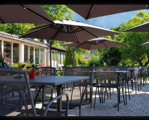 un patio extérieur avec des tables, des chaises et des parasols dans l'établissement Restaurant Les Vérines, à Chamoson