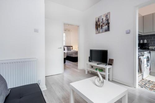 a white living room with a couch and a tv at CONEN Chert Apartment in London