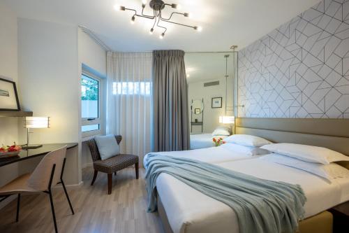 a bedroom with a large bed and a desk and chair at Maxim Design Hotel 3 Star Superior in Tel Aviv