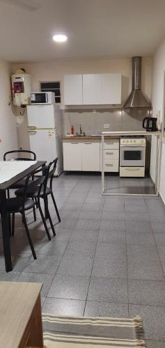 una cocina con electrodomésticos blancos, mesa y sillas en APART CENTER en Villa María