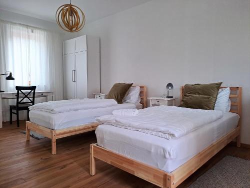 2 Betten in einem Zimmer mit weißen Wänden und Holzböden in der Unterkunft Quartier35 