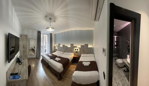 Habitación de hotel con 2 camas y sofá en Hostal Anton Martin en Madrid