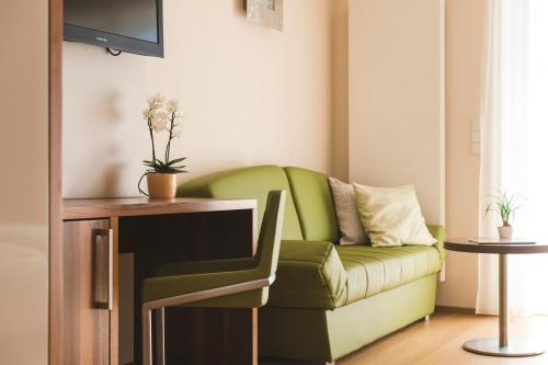 a living room with a green couch and a table at Hotel Residence Pernhof in Termeno