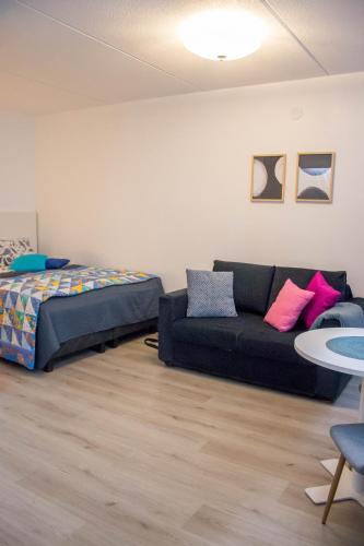 una sala de estar con un sofá y una cama en HighHill Lahti City apartment, en Lahti
