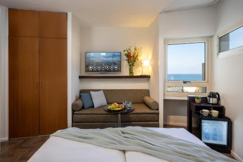 a bedroom with a bed and a couch and a tv at Maxim Design Hotel 3 Star Superior in Tel Aviv