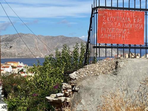 a sign on the side of a rock with a mountain at Little Blue in Chorio, Symi in Symi