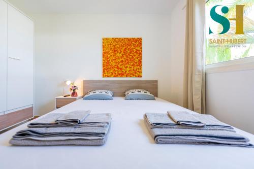 - une chambre avec un lit blanc et des serviettes dans l'établissement "Le Cosy", 2 chambres, Centre-ville de Saint-Denis, à Saint-Denis