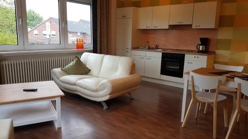 ein Wohnzimmer mit einer weißen Couch und einer Küche in der Unterkunft Ferienwohnungen Brasse in Dornumersiel