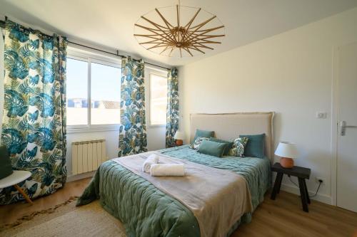 een slaapkamer met een groot bed met blauwe gordijnen en een kroonluchter bij Le Boudoir du Palais Climatisé & Luxueux in Périgueux