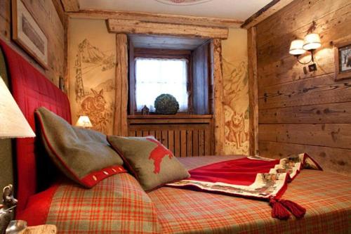 Un dormitorio con una cama con una manta roja. en La Petite, en Courmayeur