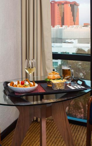 a table with a plate of food and a glass of wine at Hotel Guadalajara Plaza Expo in Guadalajara