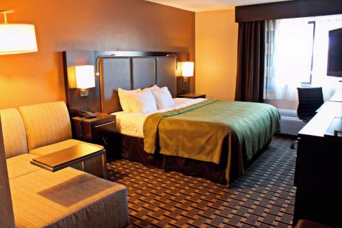 Quality Inn & Suites Detroit Metro Airport في رومولوس: غرفه فندقيه بسرير وكرسي