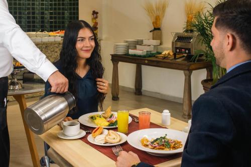 a woman is pouring coffee into a plate of food at Hotel Guadalajara Plaza Expo in Guadalajara