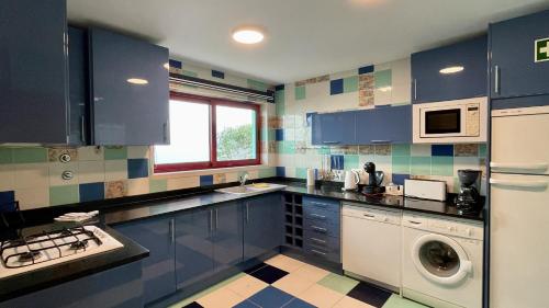 a kitchen with blue cabinets and a washing machine at Marina - Private Pool - 10 Pax - Albufeira in Albufeira