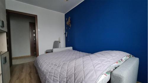a bedroom with a bed with a blue wall at Spokojny Wypoczynek 4 in Ostrów Wielkopolski