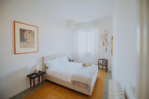 a white bedroom with a bed and a chair at A casa di Giulia in Latina