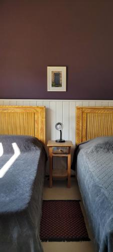 um quarto com 2 camas e uma mesa com um candeeiro em La Trinca Casas Charmosas em São Bento do Sapucaí