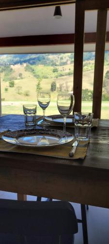 uma mesa com um prato com copos de vinho em La Trinca Casas Charmosas em São Bento do Sapucaí