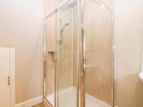 una doccia con porta in vetro in bagno di White Hillocks Farm House a Inchmill