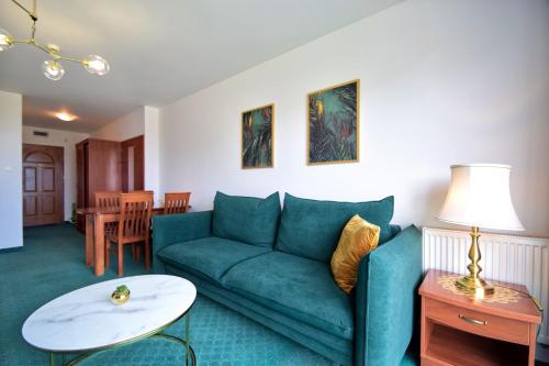 a living room with a blue couch and a table at Apartamenty Kołobrzeg Morska in Kołobrzeg