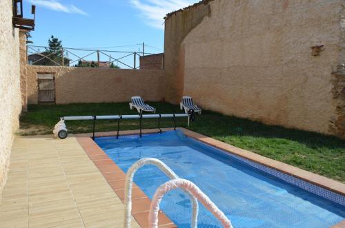 einen Pool mit zwei Stühlen neben einem Gebäude in der Unterkunft Casa de los Balcones La Bañeza León 
