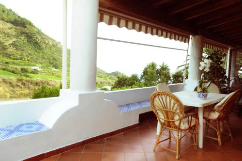 eine Veranda mit einem Tisch und Stühlen sowie einem großen Fenster in der Unterkunft CASA LA ROSA in Leni