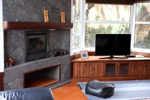 a living room with a tv and a fireplace at Casa Cor de Rosa in Madalena