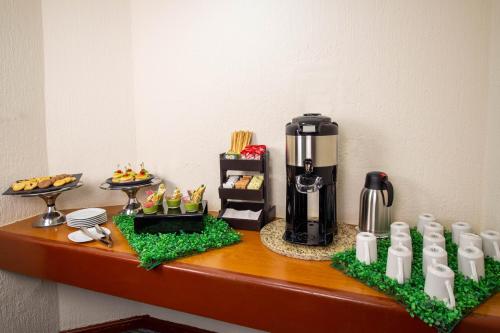 a table with a coffee maker and food on it at Hotel Guadalajara Plaza Expo in Guadalajara