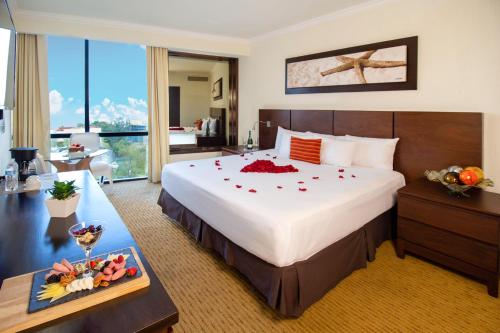 瓜達拉哈拉的住宿－瓜達拉哈拉世博廣場酒店，酒店客房设有一张大床和一张带食物的桌子。