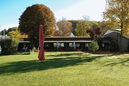 un paraguas rojo en el patio de una casa en Pension am See en Wörthsee