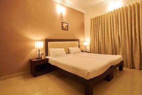 a bedroom with a bed with two night stands and two lamps at Fort Abode in Cochin