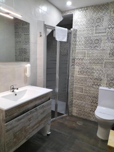 a bathroom with a sink and a shower and a toilet at Apartamentos Lares in Santa Olalla