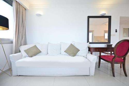 a white living room with a white couch and a desk at Orchid Hotel by HolyGuest in Tel Aviv