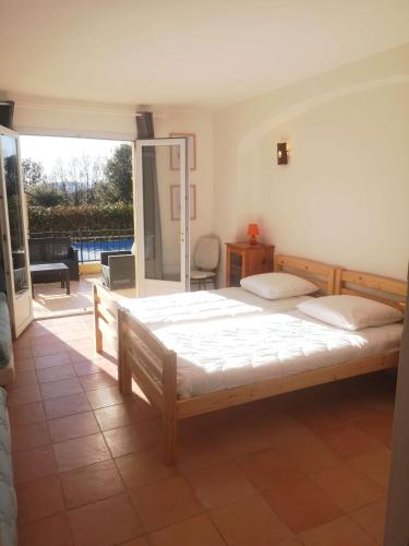 a bedroom with a large bed and a balcony at Chez TATA in Régusse