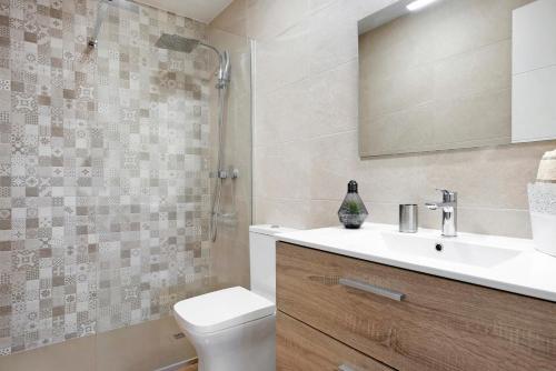 a bathroom with a sink and a toilet and a mirror at Apartamento Almar in Chiclana de la Frontera