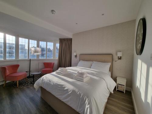 a bedroom with a large white bed with two red chairs at Hotel CG London in London