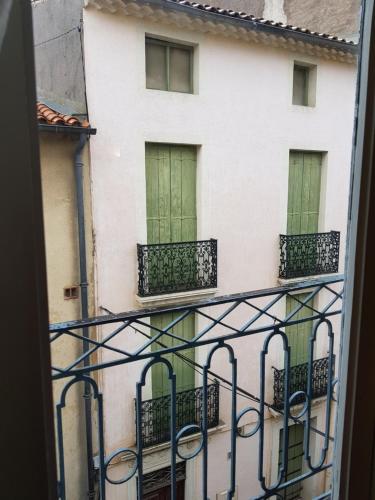 a building with green doors and balconies from a window at Au QUATRE, 2em étage centre historique in Pézenas