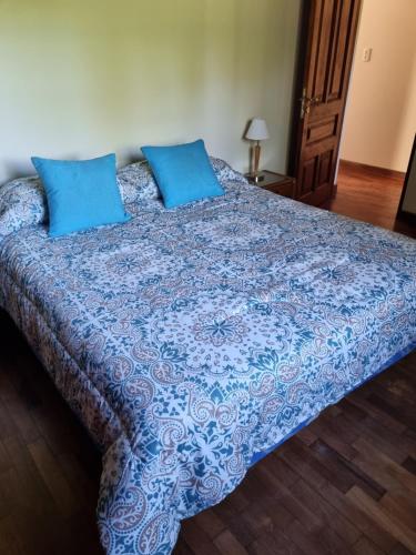 a large bed with blue sheets and blue pillows at La Soleada in San Lorenzo