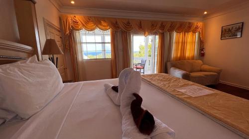 a bedroom with a large white bed with two towels at All Nations Guest House in Port Antonio