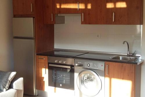 een keuken met een wasmachine en een wastafel bij Coqueto alojamiento cercano a las termas in Ourense