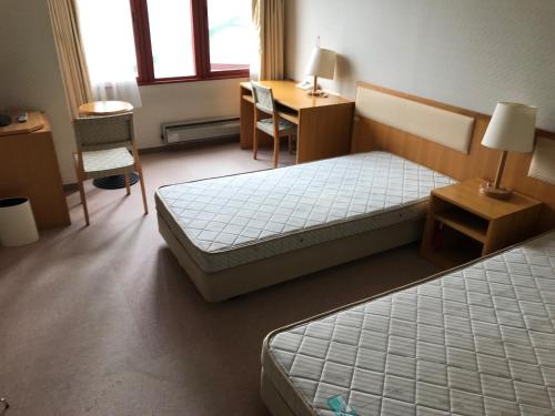 a bedroom with two beds and a desk and a table at Aizu Kogen International Human Resources Center - Vacation STAY 34895v in Minamiaizu