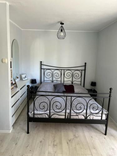 a bedroom with a black bed and a chandelier at Apartament Baltic Sea in Gdańsk